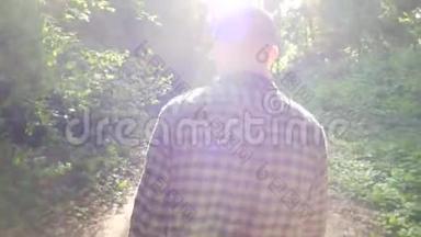 一个人沿着一条森林小径走。 摄像机从后面跟着那个人。